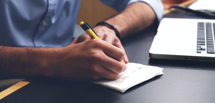 Free Person Writing on Paper Using Yellow and Black Pen Stock Photo