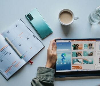 person using Windows 11 computer beside white ceramic mug on white table