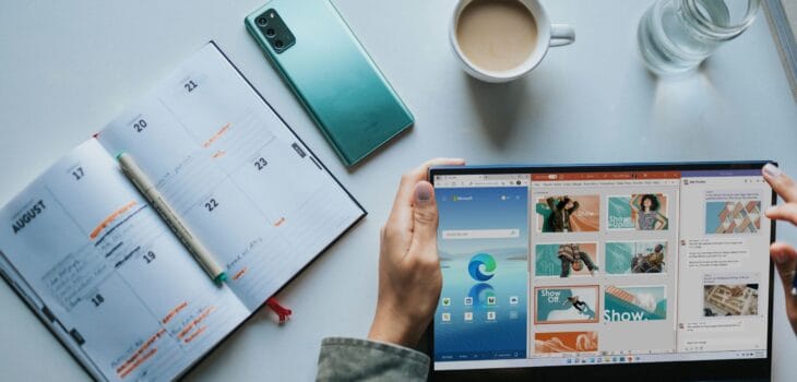 person using Windows 11 computer beside white ceramic mug on white table