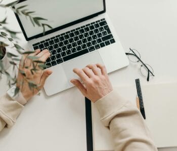 Free An overhead view of a person working on a laptop in a minimalist home office setting. Stock Photo