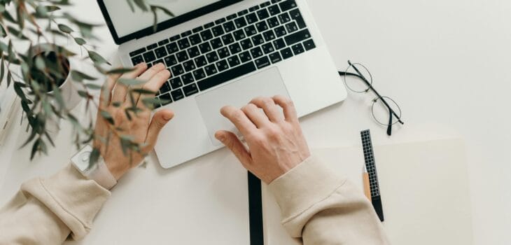 Free An overhead view of a person working on a laptop in a minimalist home office setting. Stock Photo