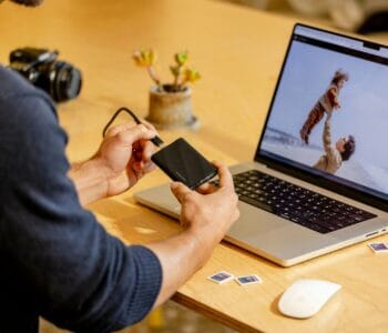 A man sitting at a table with a laptop and cell phone