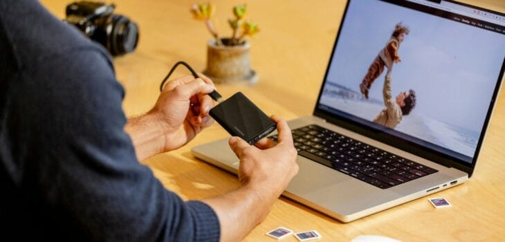 A man sitting at a table with a laptop and cell phone