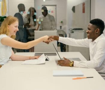 Free Business professionals completing a successful deal with a handshake in a modern office setting. Stock Photo