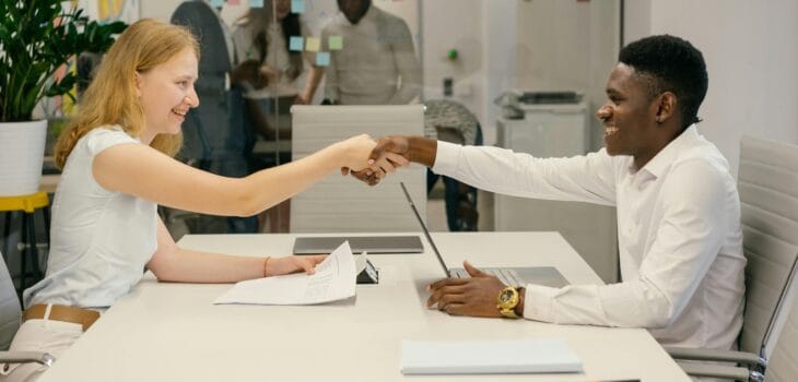 Free Business professionals completing a successful deal with a handshake in a modern office setting. Stock Photo