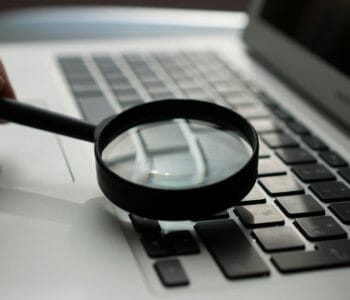 magnifying glass near gray laptop computer