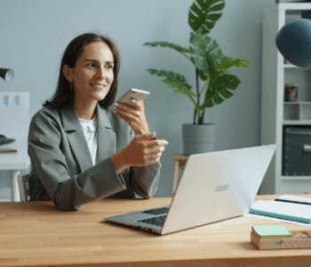 lady holding phone while working on a laptop